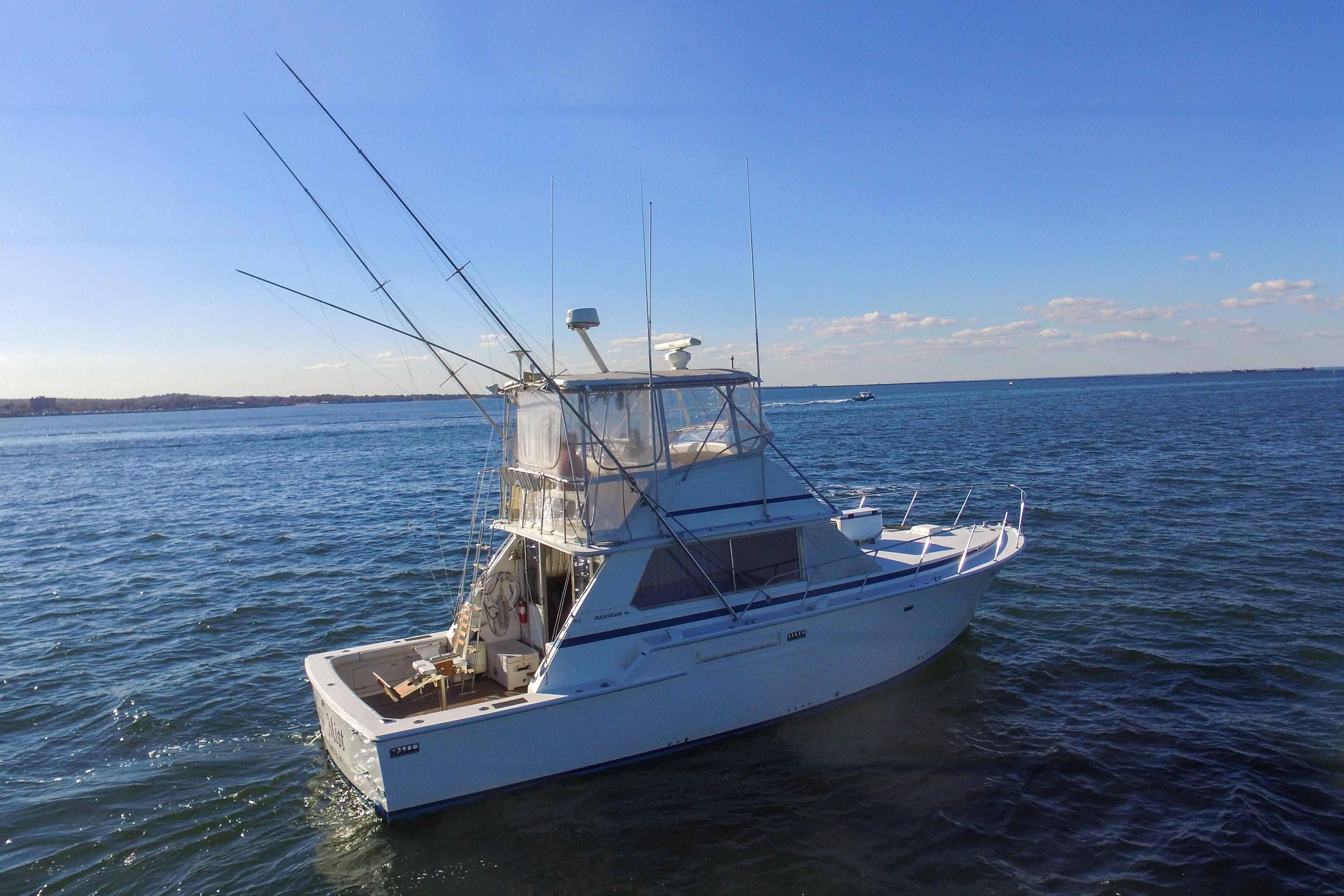 1980 Bertram 42 Convertible yacht on open water under clear blue sky.