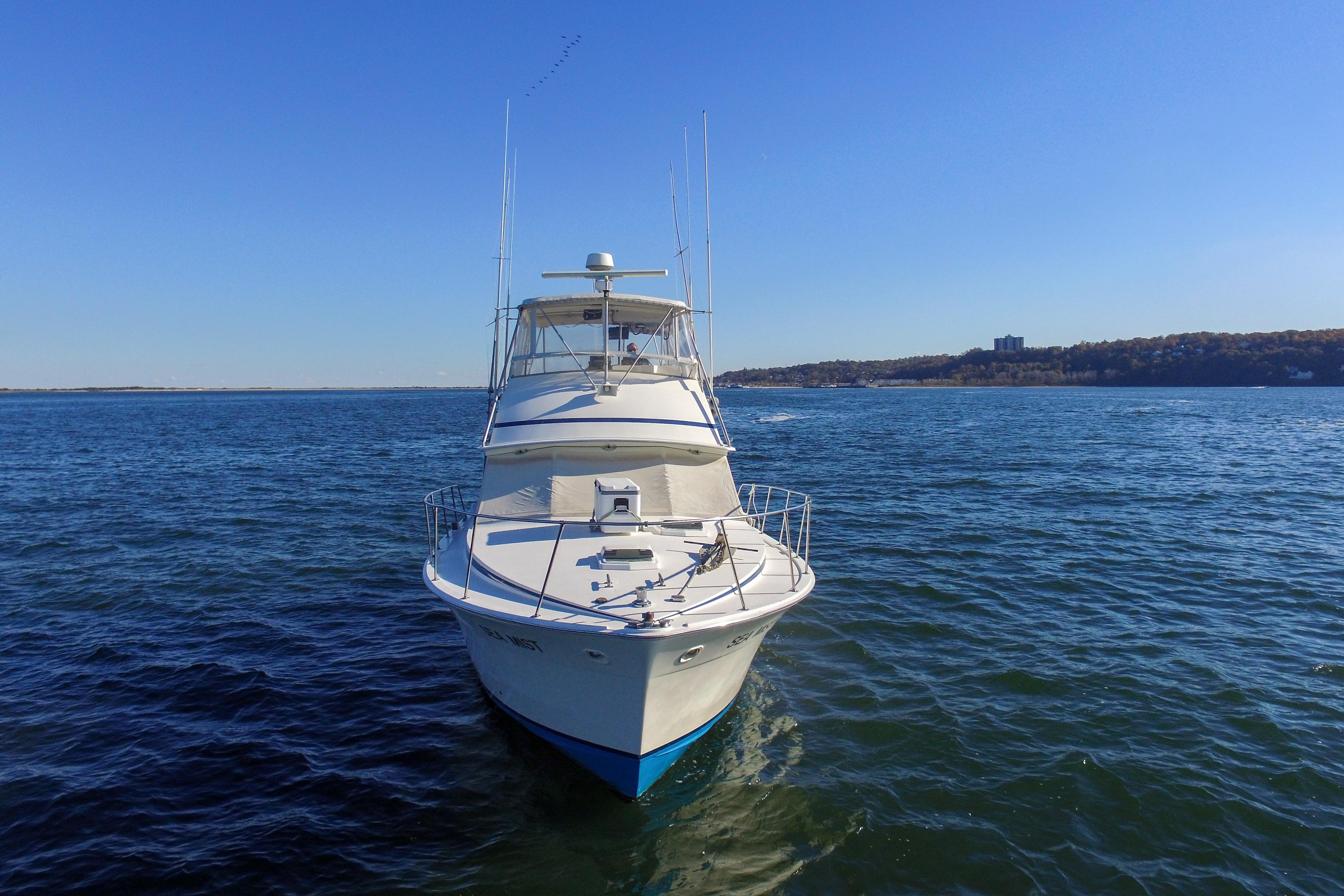 1980 Bertram 42 Convertible yacht on open water under clear blue sky.
