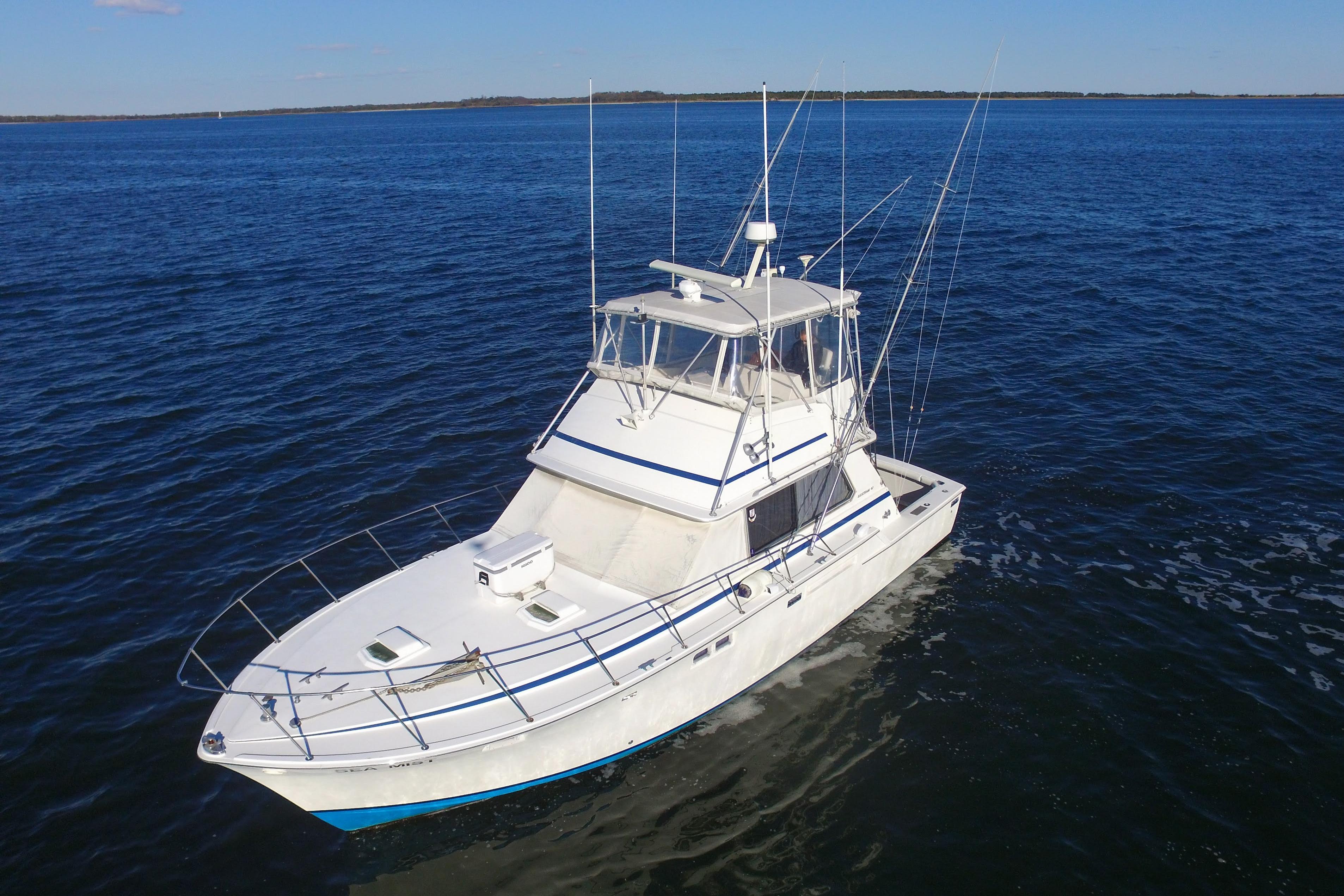 1980 Bertram 42 Convertible boat on open water, clear blue sky.