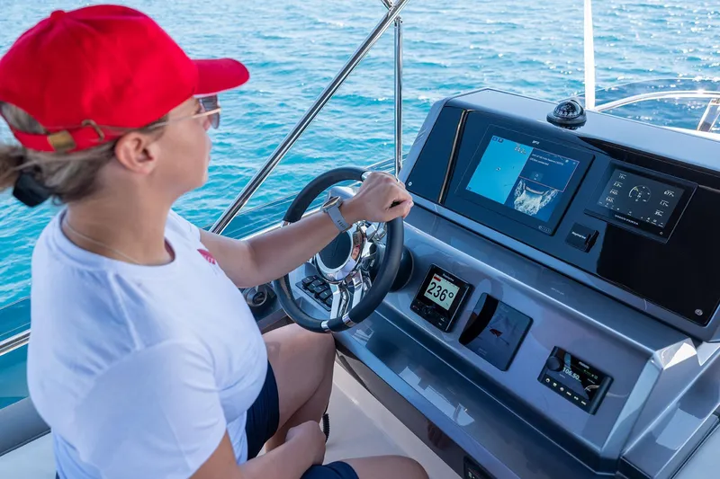  Yacht Photos Pics Person steering 2023 Galeon 500 Fly yacht on open water, focusing on navigation controls.