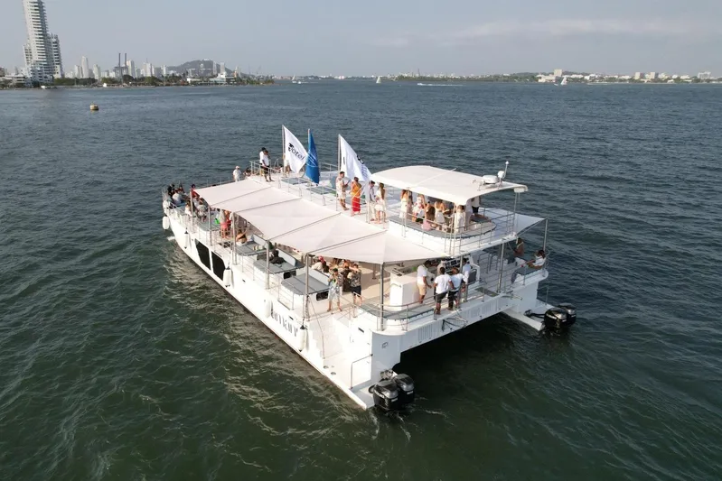  Yacht Photos Pics Aerial view of Custom PAXCAT 2027 catamaran with passengers on deck, sailing near city skyline.
