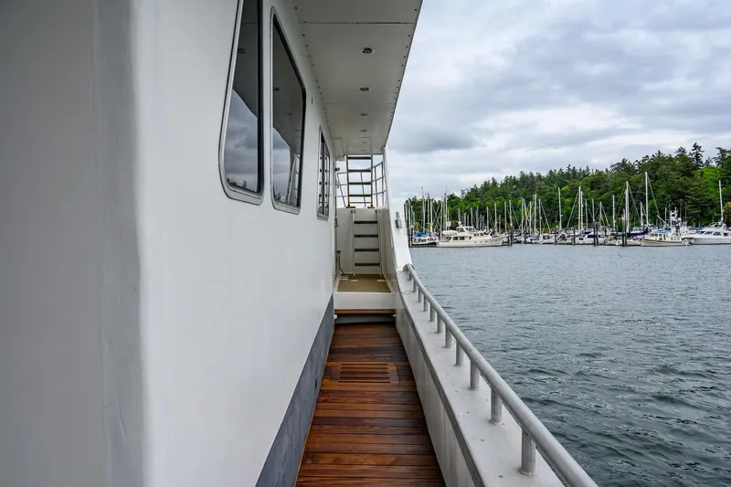 Starlight Yacht Photos Pics Side deck of 1986 Custom Expedition Vessel 58, overlooking marina with sailboats and cloudy sky.