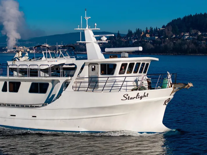 Starlight Yacht Photos Pics Custom Expedition Vessel 58, 1986, cruising on a scenic waterway with distant hills.