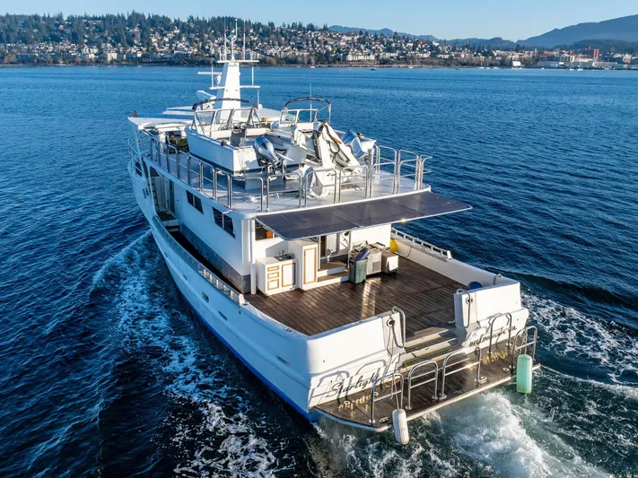 Starlight Yacht Photos Pics Custom Expedition Vessel 58, 1986, cruising on a scenic waterway with cityscape in the background.