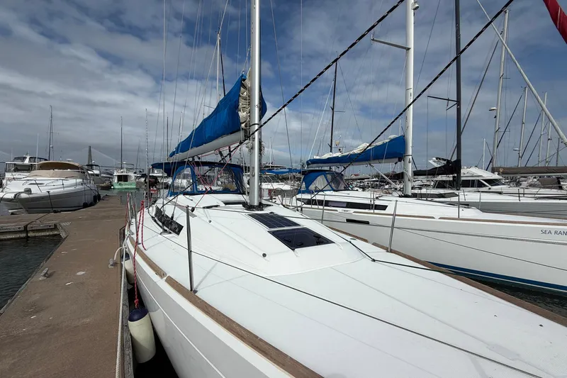 Layover Yacht Photos Pics 2018 Jeanneau Sun Odyssey 389 sailboat docked in a marina under a cloudy sky.