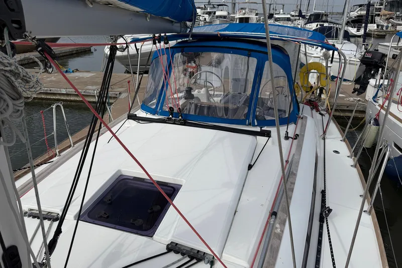 Layover Yacht Photos Pics 2018 Jeanneau Sun Odyssey 389 sailboat docked at marina, featuring blue canopy and sleek deck design.