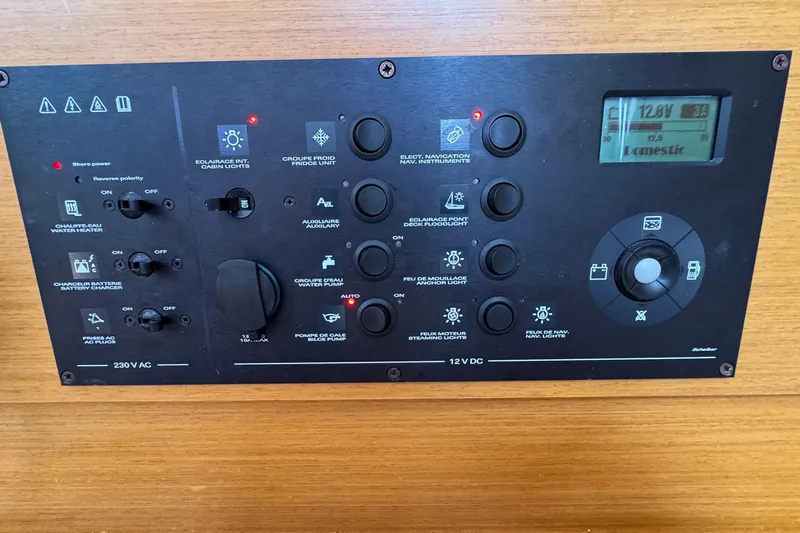 Layover Yacht Photos Pics Control panel of a 2018 Jeanneau Sun Odyssey 389 sailboat, featuring various switches and a digital display.