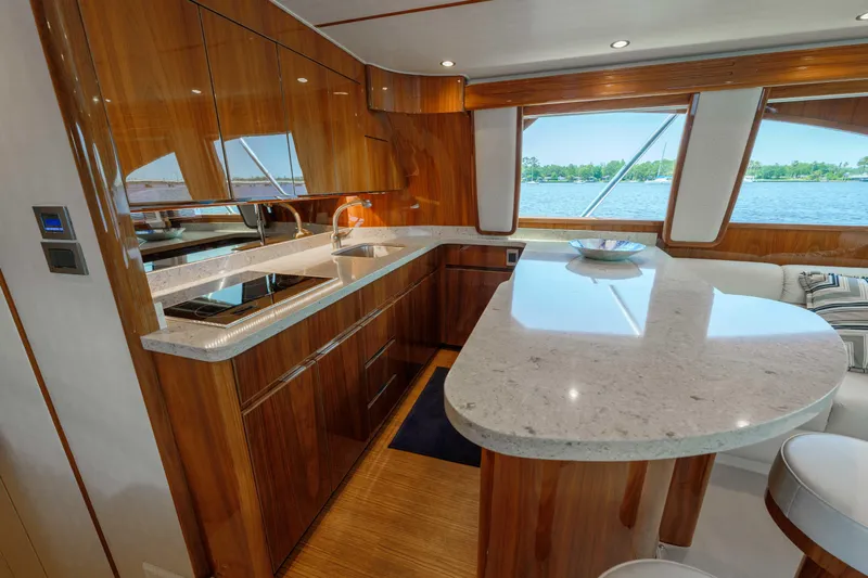 Time Away Yacht Photos Pics Luxurious kitchen interior of 2019 Viking 48 Convertible yacht with wooden cabinetry and marble countertops.