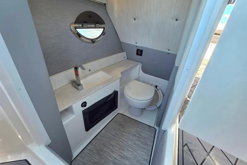  Yacht Photos Pics 2024 Cobalt R8 Outboard boat interior bathroom with sink, toilet, and porthole window.