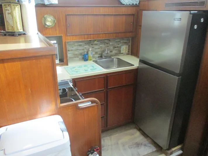  Yacht Photos Pics 1986 Hatteras 43 Double Cabin kitchen with wood cabinetry, stainless steel fridge, and compact sink.