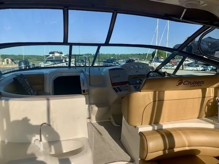  Yacht Photos Pics 1998 Cruisers Yachts 3870 Express cockpit with tan seating and control panel, docked at marina.