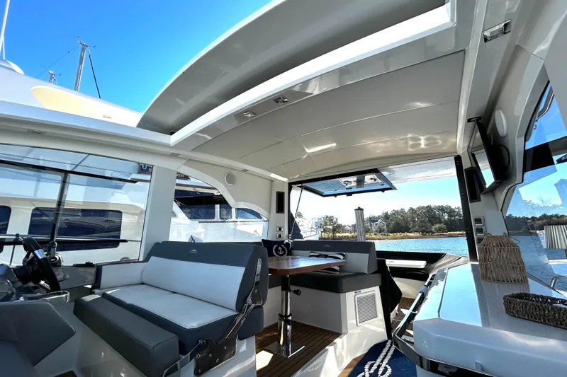 Zantical Yacht Photos Pics 2020 Galeon 425 HTS yacht interior with seating, table, and open roof, docked by water.