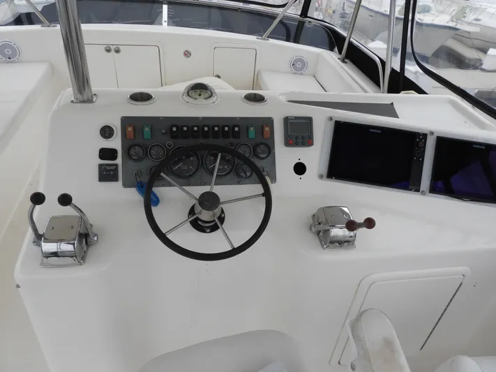  Yacht Photos Pics 1998 Riviera Convertible boat helm with steering wheel, control panel, and navigation screens.