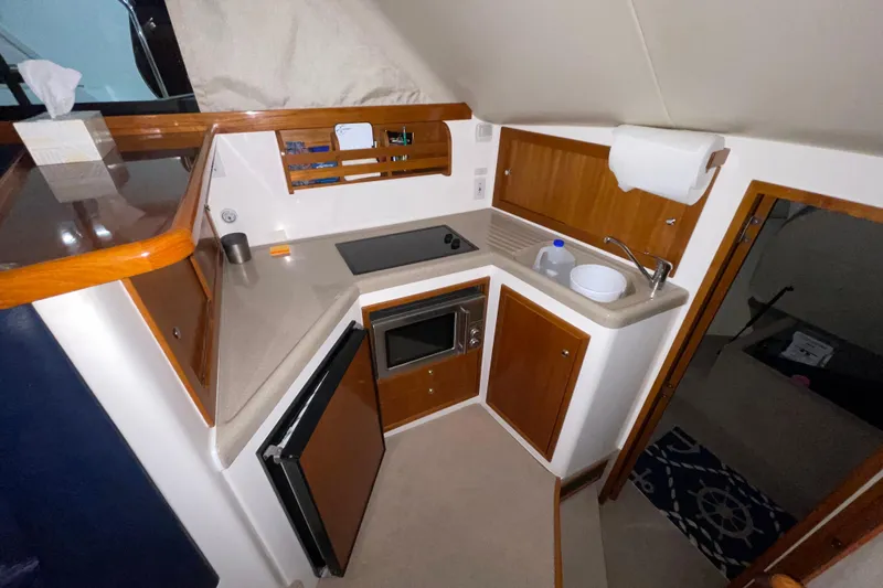  Yacht Photos Pics Compact kitchen area in a 2002 Riviera 34 Convertible boat, featuring modern amenities.