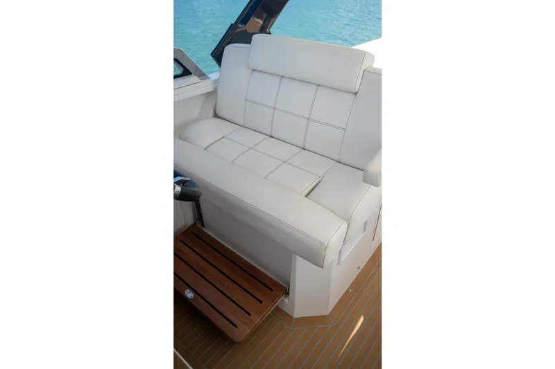  Yacht Photos Pics 2018 Cruisers Yachts 390 Express Coupe helm seat with white upholstery and wooden footrest.