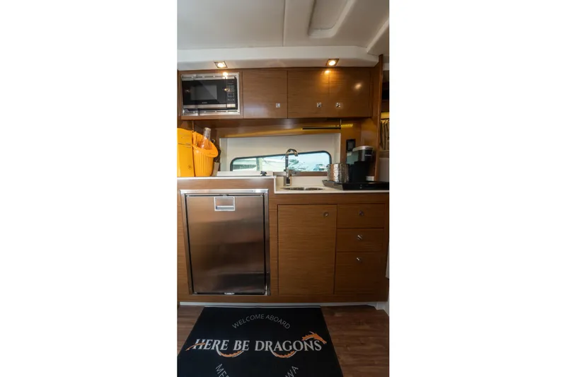  Yacht Photos Pics 2018 Cruisers Yachts 390 Express Coupe kitchen interior with modern appliances and wood cabinetry.