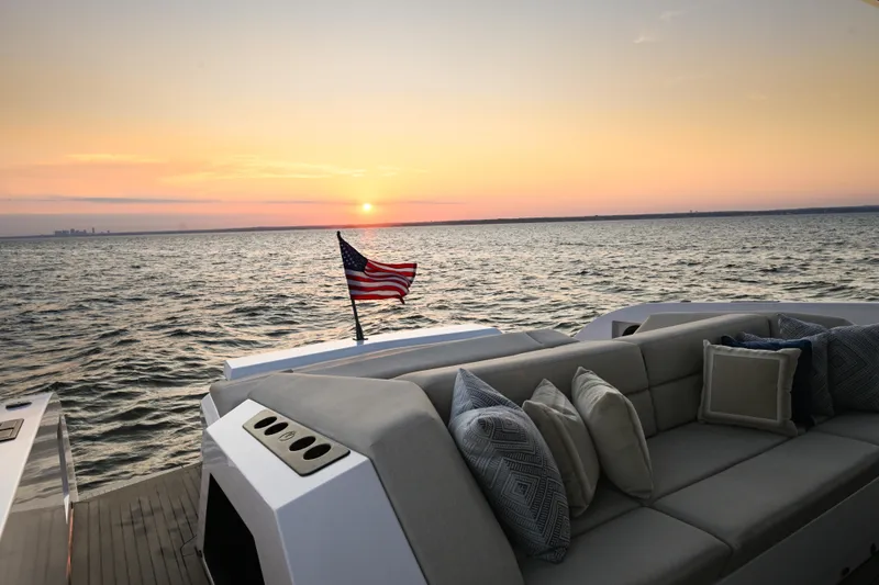 Take It Easy V Yacht Photos Pics Luxury Vanquish VQ58 yacht at sunset, featuring elegant seating and an American flag.