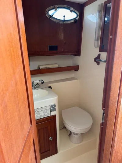  Yacht Photos Pics 2006 Albemarle 320 Express Fisherman boat bathroom with sink, toilet, and wooden cabinetry.