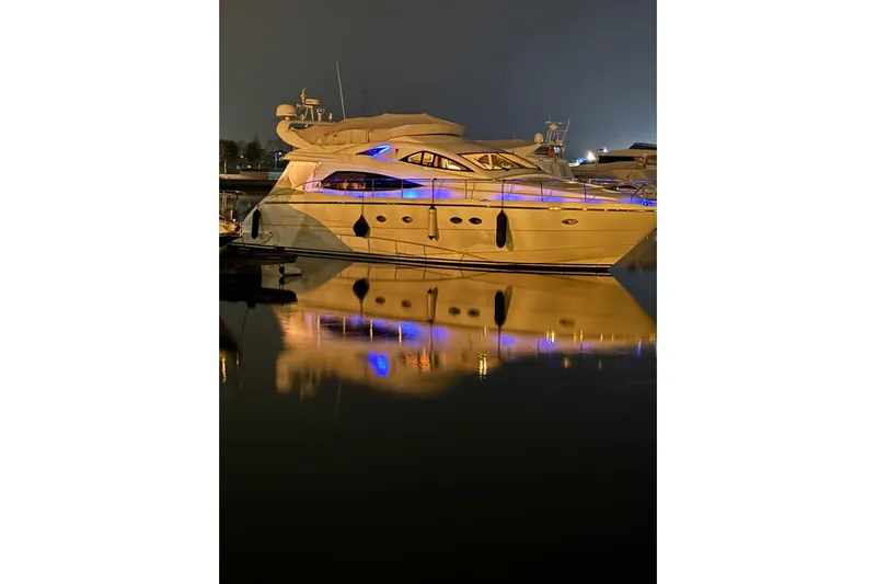  Yacht Photos Pics Aicon 56 yacht, 2006 model, illuminated at night, reflecting on calm water.