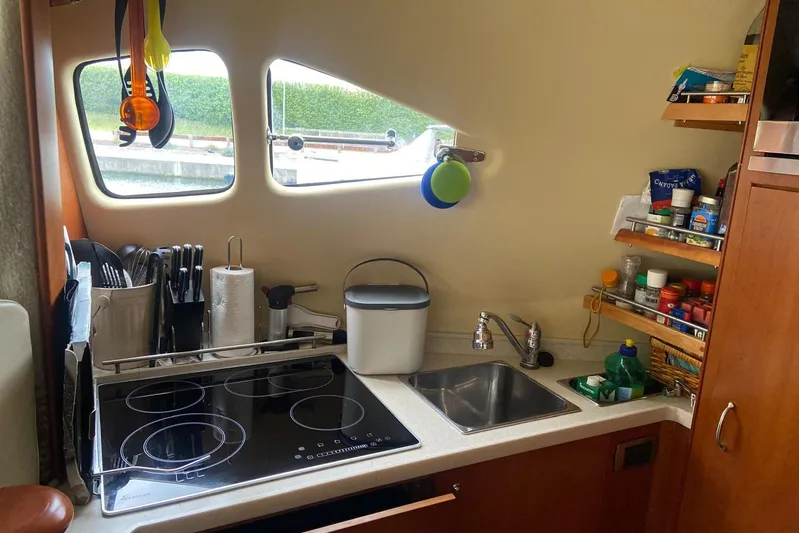  Yacht Photos Pics Compact kitchen in a 2006 Aicon 56 yacht with stove, sink, and storage shelves.