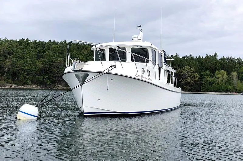 San Juan Explorer Yacht Photos Pics 2020 American Tug 362 anchored in scenic waters with forested background.