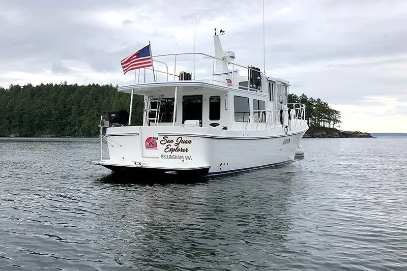 San Juan Explorer Yacht Photos Pics American Tug 362, 2020 model, cruising in scenic waters with forested shoreline.