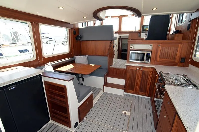 San Juan Explorer Yacht Photos Pics Interior of 2020 American Tug 362, featuring kitchen, dining area, and wooden cabinetry.