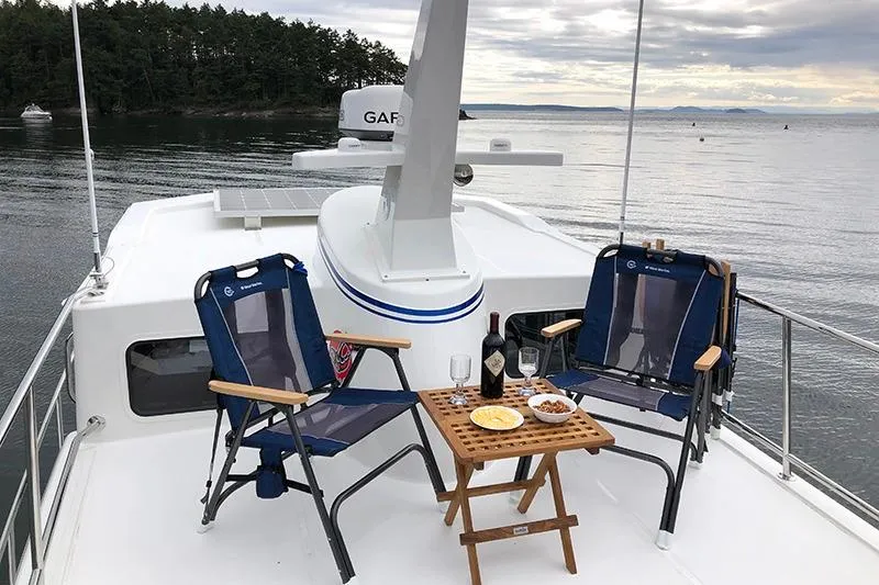 San Juan Explorer Yacht Photos Pics 2020 American Tug 362 deck with chairs, table, wine, and snacks, overlooking serene waters.