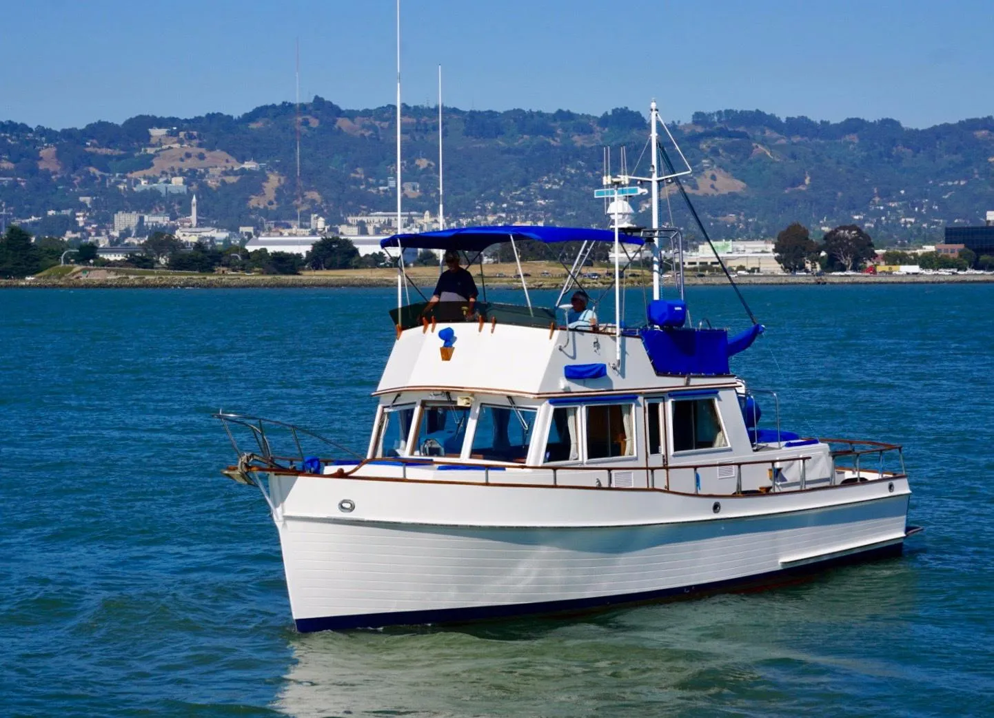 1982 Grand Banks Classic boat cruising on a scenic lake with hills in the background.