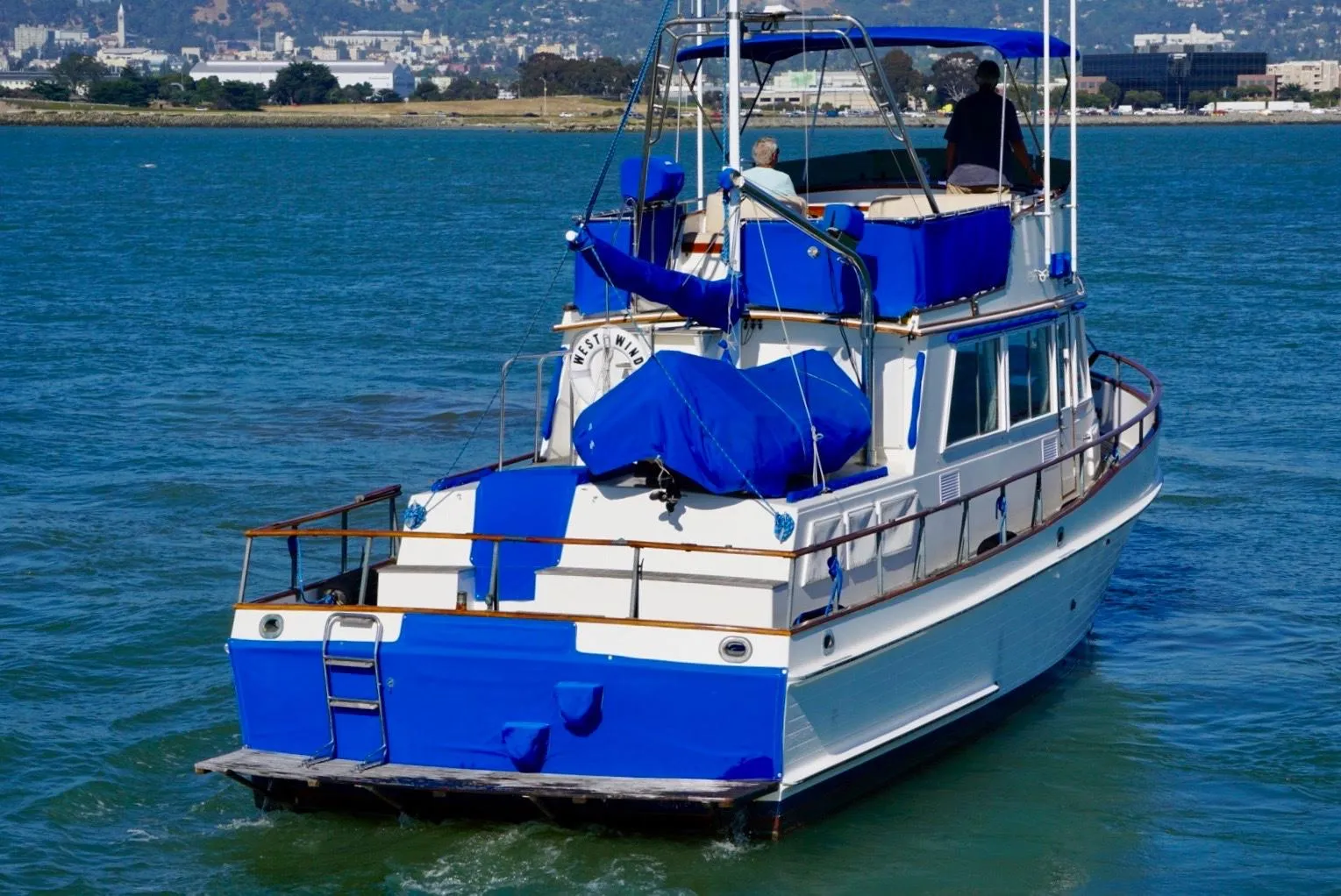 1982 Grand Banks Classic yacht cruising on a sunny day, featuring blue and white design.