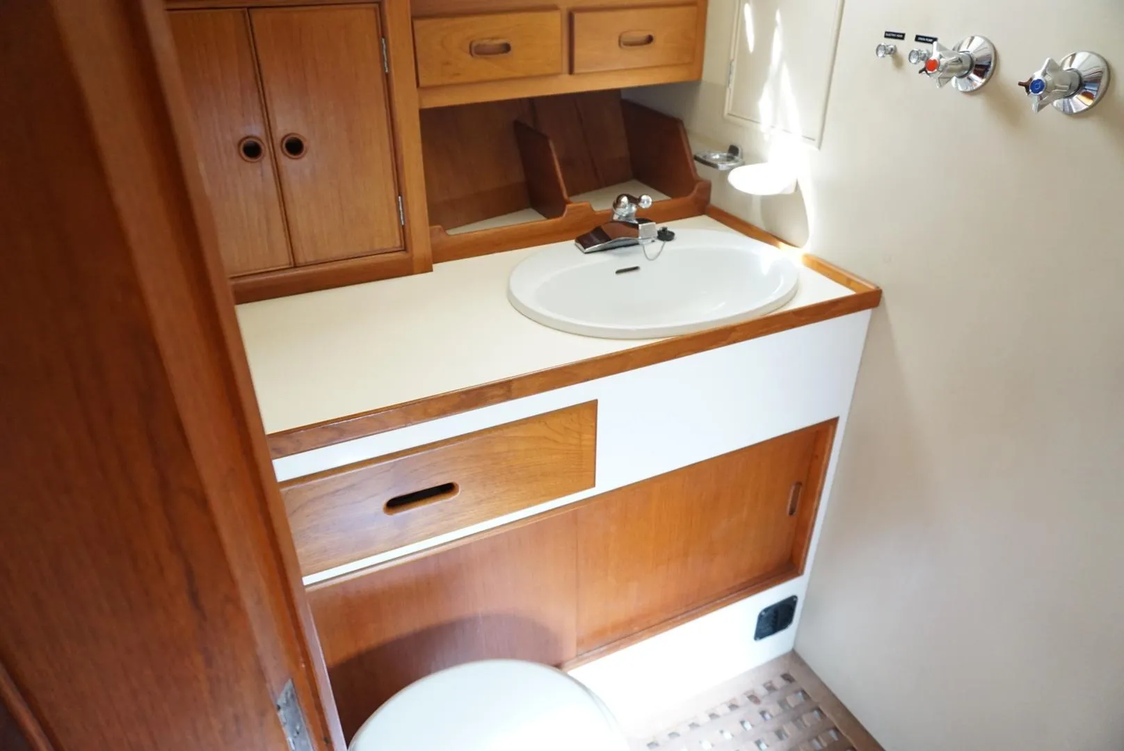 1982 Grand Banks Classic yacht bathroom with wooden cabinetry and white sink.