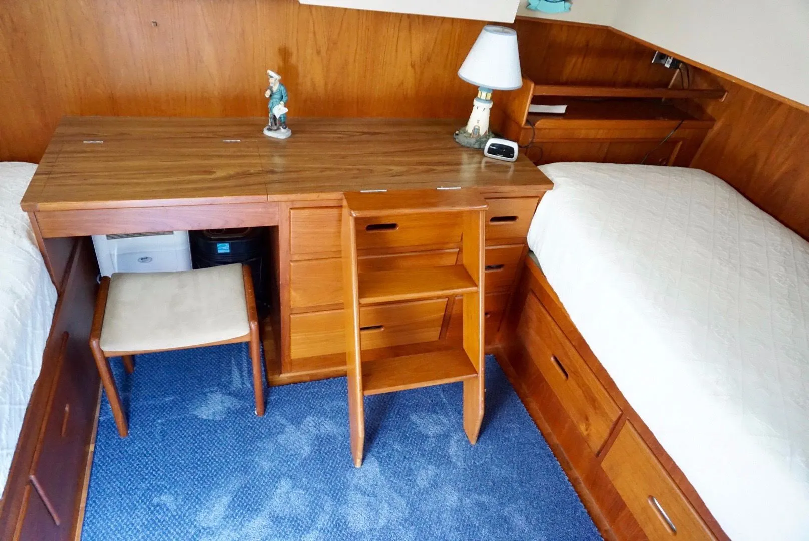 1982 Grand Banks Classic cabin interior with wooden desk, twin beds, and blue carpet.