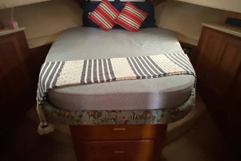 Eclipse Yacht Photos Pics 1999 Mainship 350 Trawler cabin with cozy bed, striped blanket, and decorative pillows.