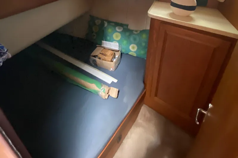 Eclipse Yacht Photos Pics 1999 Mainship 350 Trawler cabin interior with bed, pillows, and wooden cabinet.