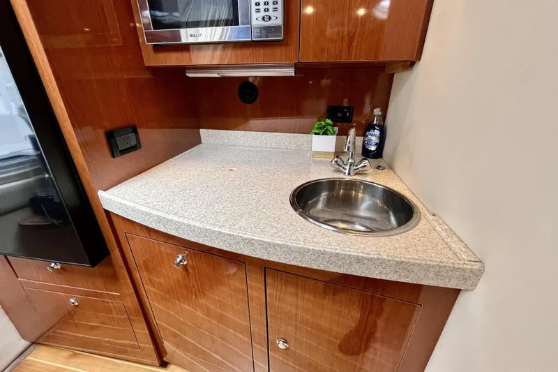  Yacht Photos Pics 2005 Regal Commodore 3560 yacht kitchenette with sink, microwave, and wooden cabinetry.