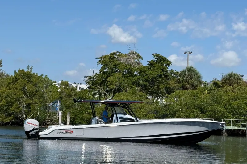  Yacht Photos Pics 2018 Nor-Tech 390 Sport Center Console boat on calm water, surrounded by lush greenery.