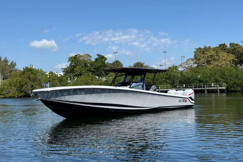  Yacht Photos Pics 2018 Nor-Tech 390 Sport Center Console boat on calm water, surrounded by greenery.