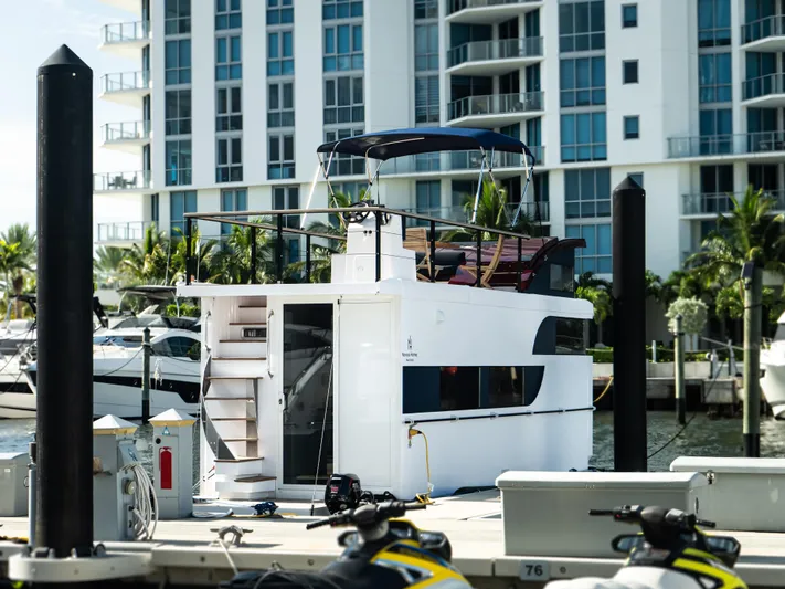  Yacht Photos Pics 2024 Navisyo Homes 28' NAVIS V.08 houseboat docked in marina, modern building backdrop.