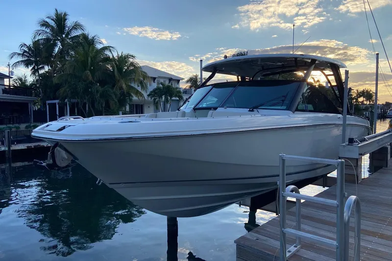  Yacht Photos Pics 2024 Boston Whaler 320 Vantage boat docked at sunset with palm trees in background.