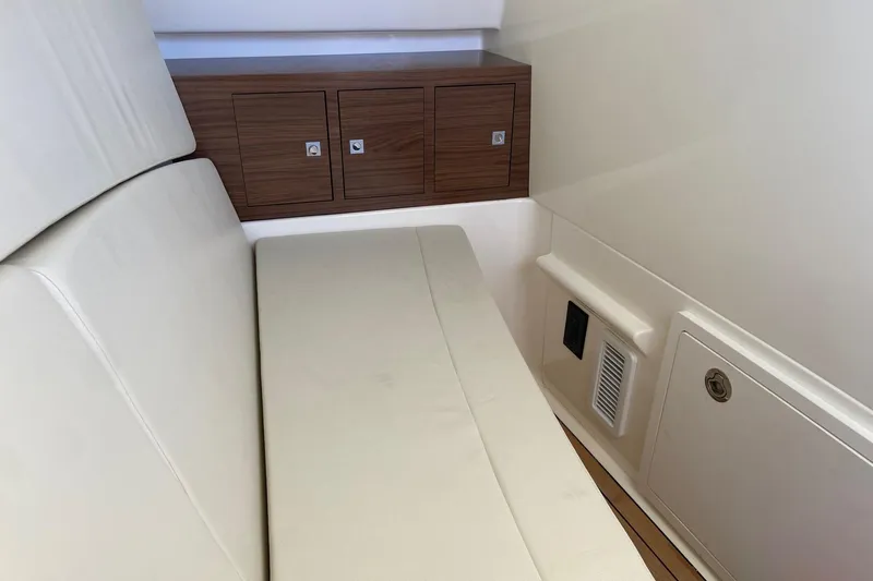  Yacht Photos Pics 2024 Boston Whaler 320 Vantage interior with cushioned seating and wooden storage cabinets.