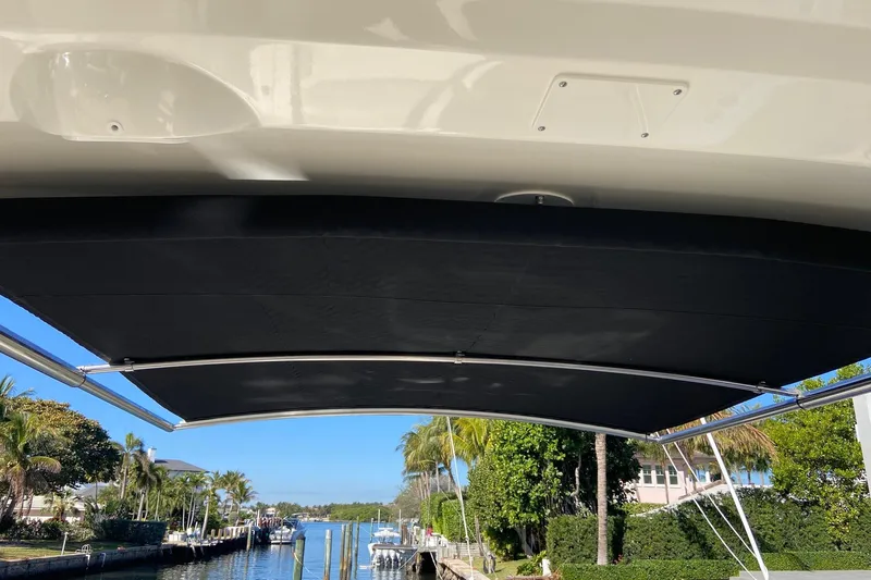  Yacht Photos Pics 2024 Boston Whaler 320 Vantage boat with sunshade, docked near palm trees and waterfront homes.