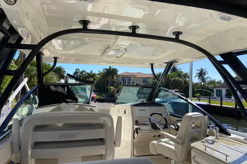  Yacht Photos Pics 2024 Boston Whaler 320 Vantage boat interior with helm and seating, docked near waterfront homes.