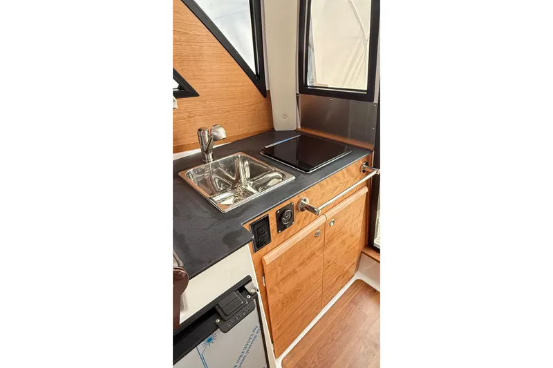  Yacht Photos Pics 2026 Cutwater C-248 Coupe interior kitchen with sink, stove, and wooden cabinetry.