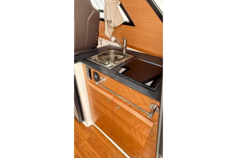  Yacht Photos Pics 2026 Cutwater C-248 Coupe interior kitchen with sink and stove, featuring wood cabinetry.