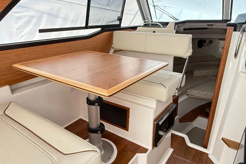  Yacht Photos Pics 2026 Cutwater C-248 Coupe interior with wooden table, cushioned seating, and modern design.