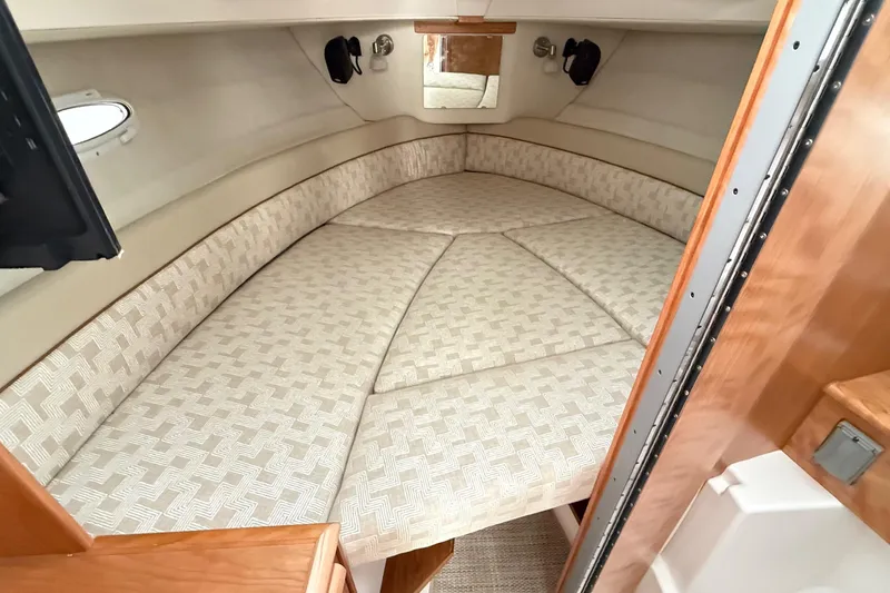  Yacht Photos Pics 2026 Cutwater C-248 Coupe interior cabin with cushioned V-berth and wooden accents.