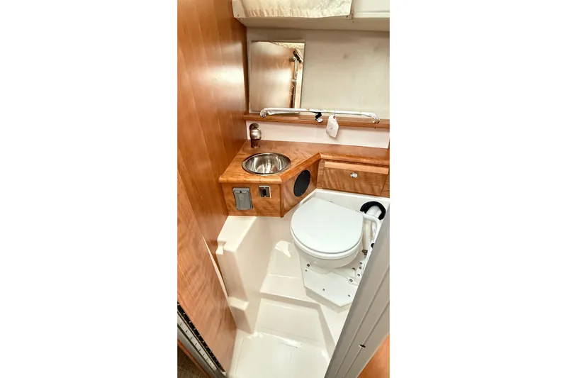  Yacht Photos Pics 2026 Cutwater C-248 Coupe bathroom with compact sink, toilet, and wooden cabinetry.