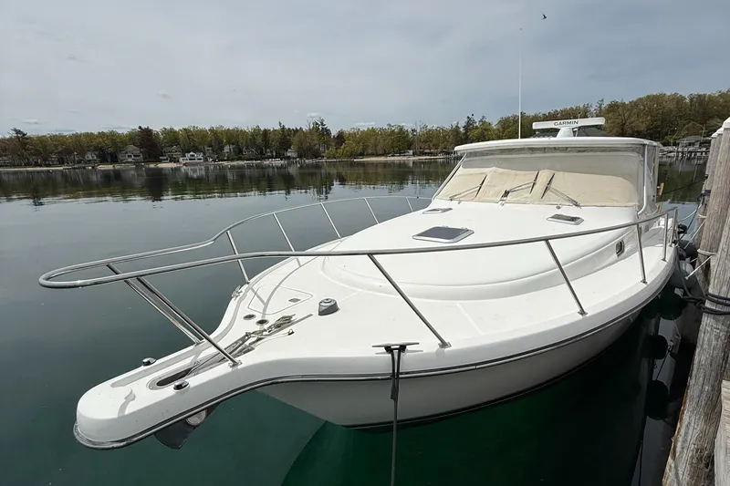  Yacht Photos Pics 2002 Pursuit 3800 Express boat docked on calm water, surrounded by trees.