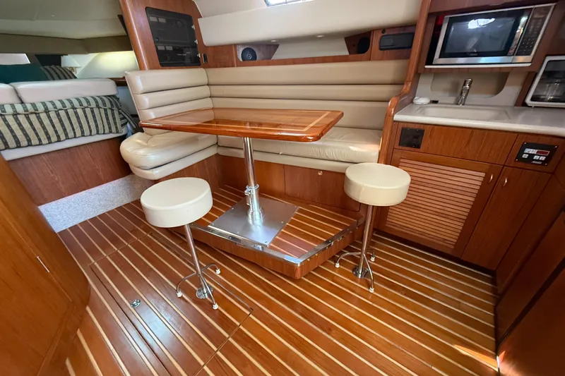  Yacht Photos Pics 2002 Pursuit 3800 Express yacht interior with wooden flooring, dining area, and kitchenette.