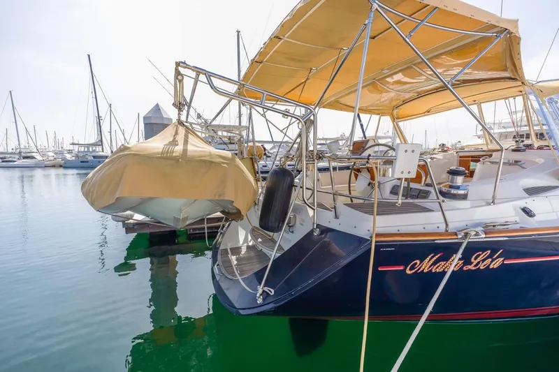 Maka Le'a Yacht Photos Pics 2006 Jeanneau DS sailboat docked in marina with tan canopy and dinghy.